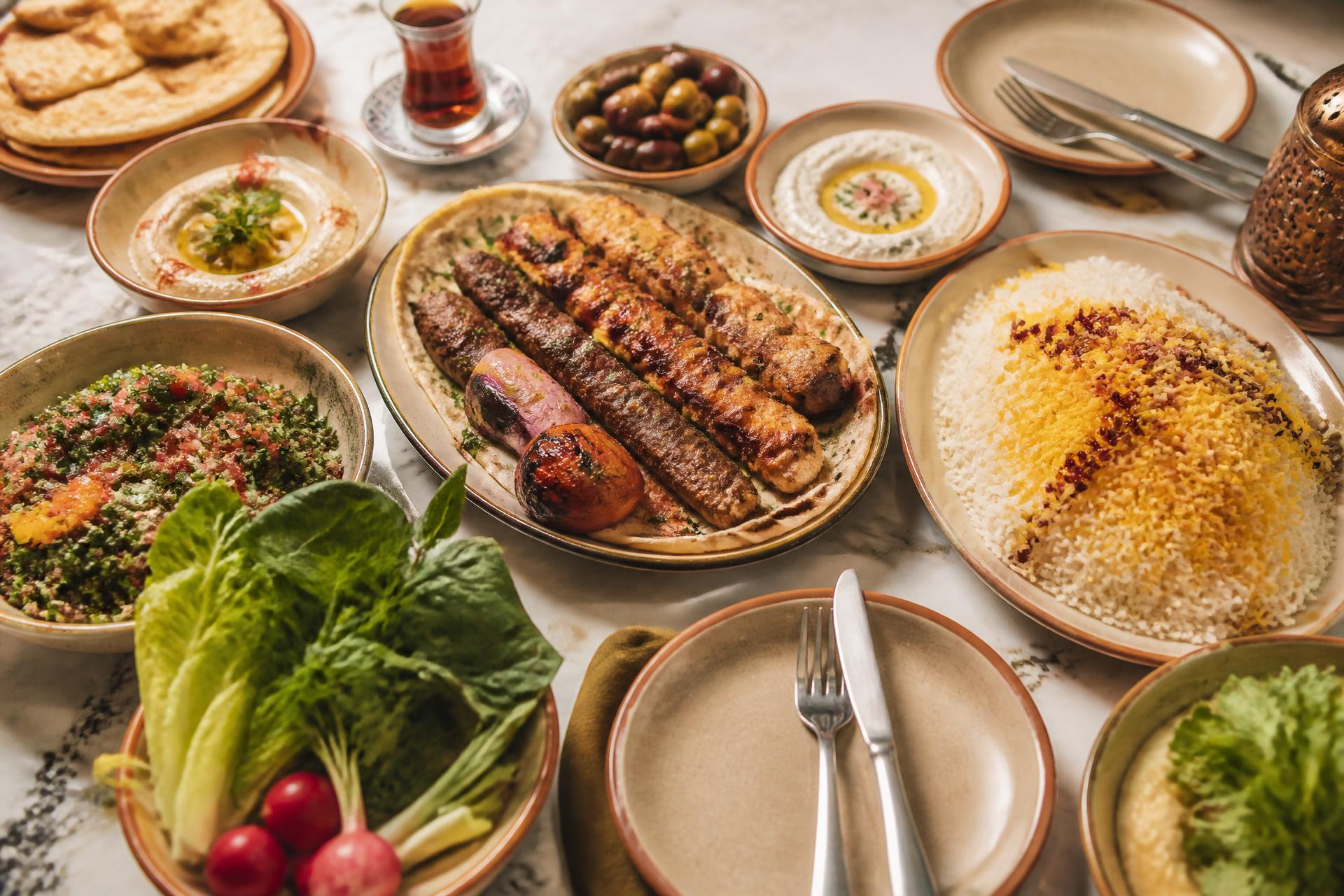 Middle Eastern restaurant table spread with grilled meats, rice and mezze
